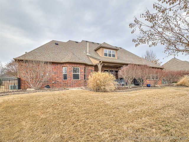 rear view of property with central AC and a yard