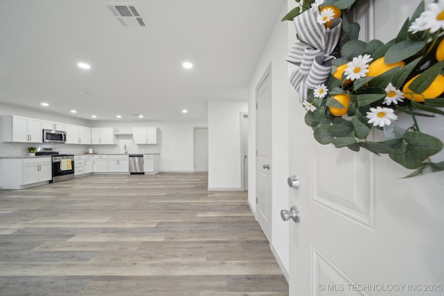 interior space with white cabinetry, appliances with stainless steel finishes, sink, and light hardwood / wood-style floors