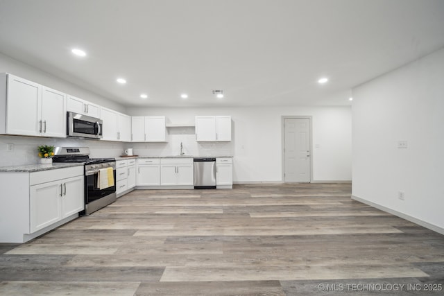 kitchen featuring sink, backsplash, stainless steel appliances, light hardwood / wood-style floors, and white cabinets