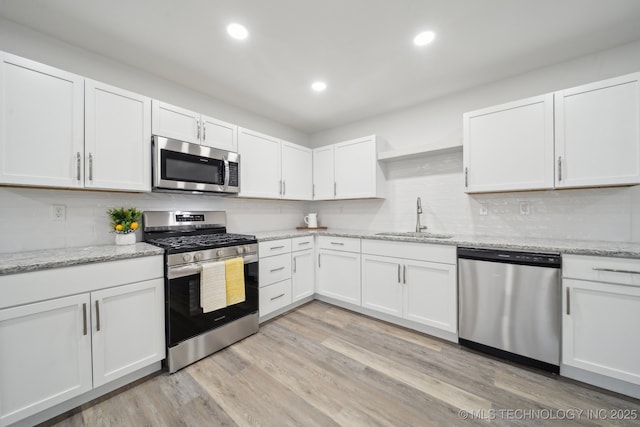 kitchen with white cabinetry, sink, light hardwood / wood-style floors, and appliances with stainless steel finishes