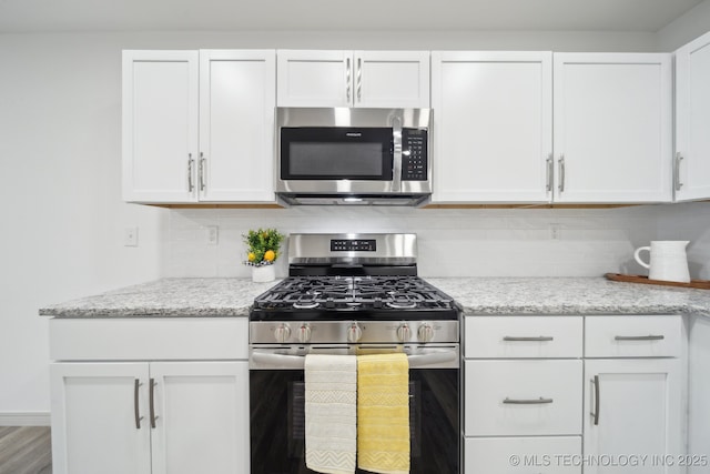 kitchen featuring white cabinetry, light stone counters, tasteful backsplash, and appliances with stainless steel finishes