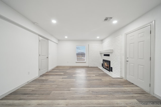 unfurnished living room with a fireplace and light wood-type flooring