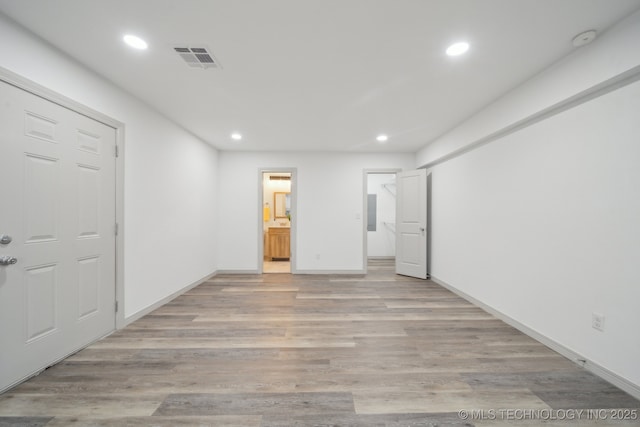 unfurnished bedroom with ensuite bathroom and light wood-type flooring