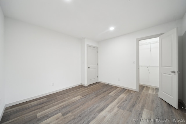 unfurnished bedroom featuring a walk in closet, wood-type flooring, and a closet