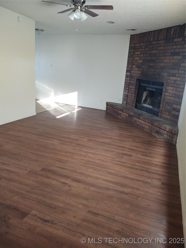 unfurnished living room with ceiling fan, dark hardwood / wood-style floors, a textured ceiling, and a fireplace