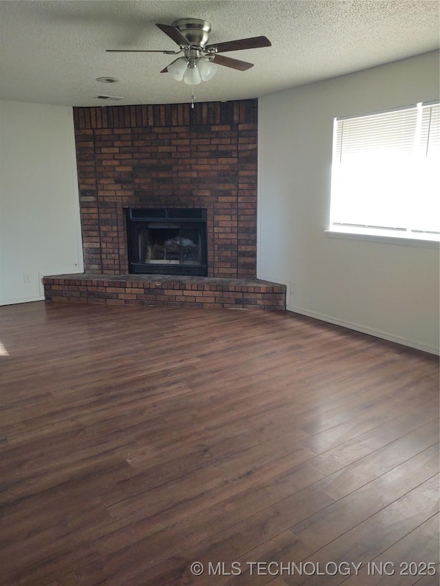 unfurnished living room with dark hardwood / wood-style floors, ceiling fan, a fireplace, and a textured ceiling