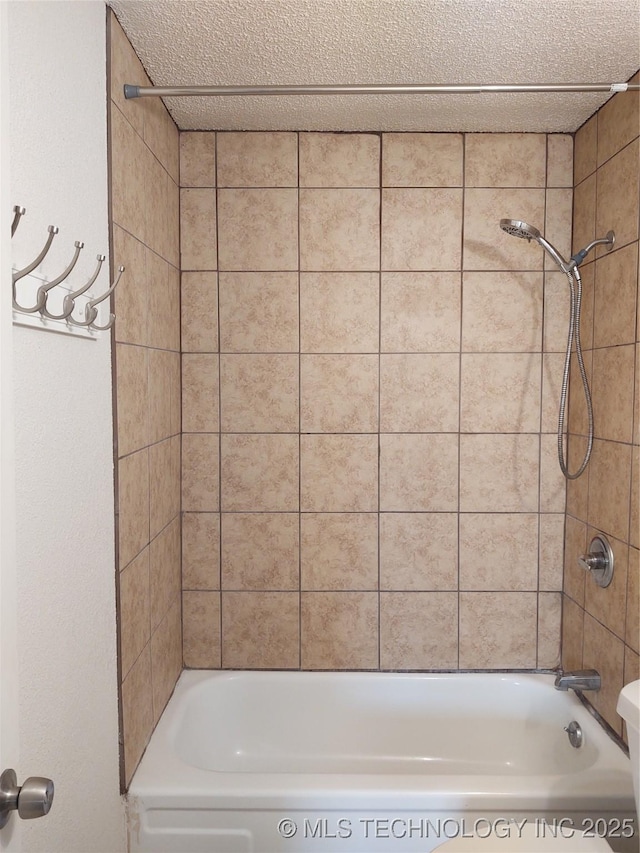 bathroom featuring tiled shower / bath and a textured ceiling