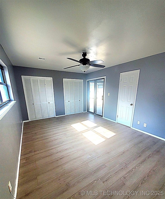 unfurnished bedroom with multiple closets, light hardwood / wood-style floors, and multiple windows