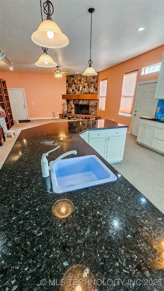 116568 S 4268th Rd, Checotah, OK 74426 - kitchen featuring a stone fireplace, a sink, open floor plan, a ceiling fan, and decorative light fixtures