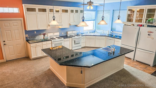 kitchen with white appliances, ceiling fan, a kitchen island with sink, white cabinets, and decorative light fixtures