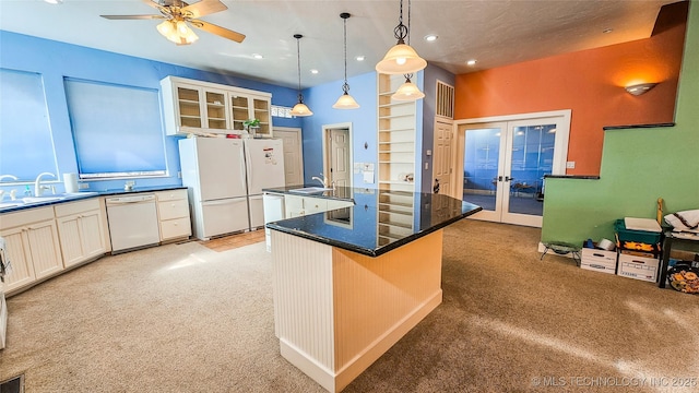 kitchen featuring french doors, sink, decorative light fixtures, a center island with sink, and white appliances