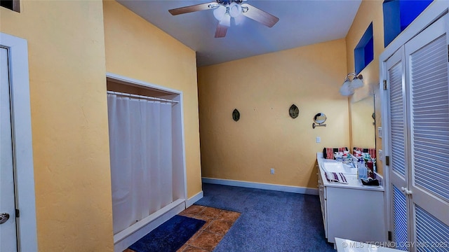 interior space with sink, ceiling fan, and dark colored carpet