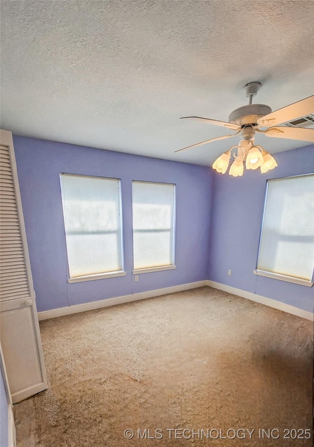 carpeted spare room featuring ceiling fan and a textured ceiling