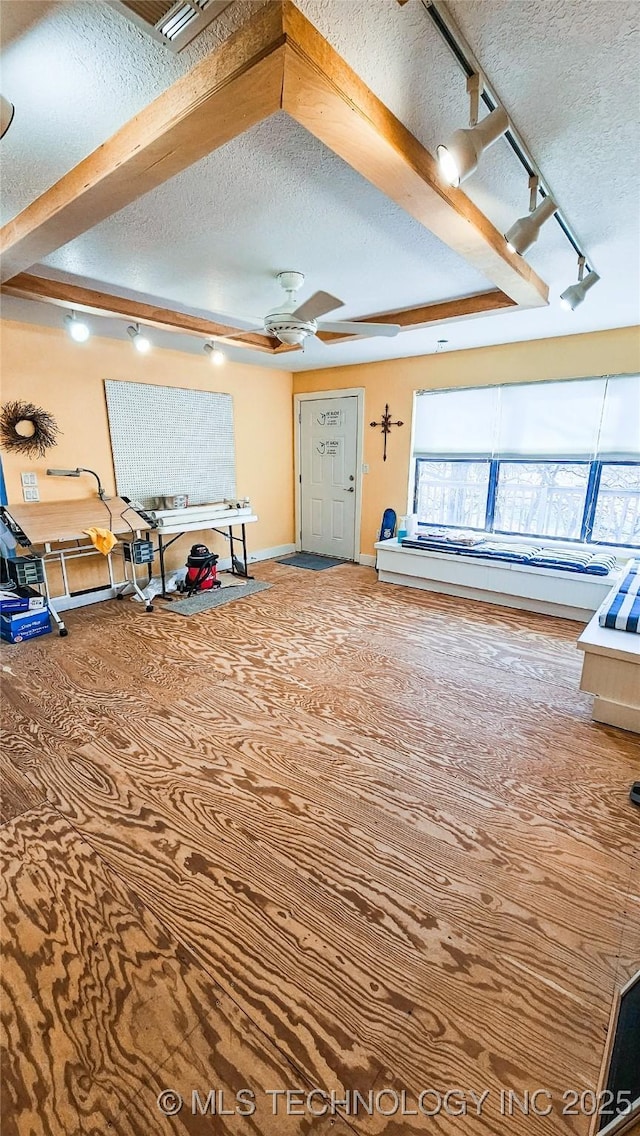 interior space featuring rail lighting, ceiling fan, a textured ceiling, and a tray ceiling