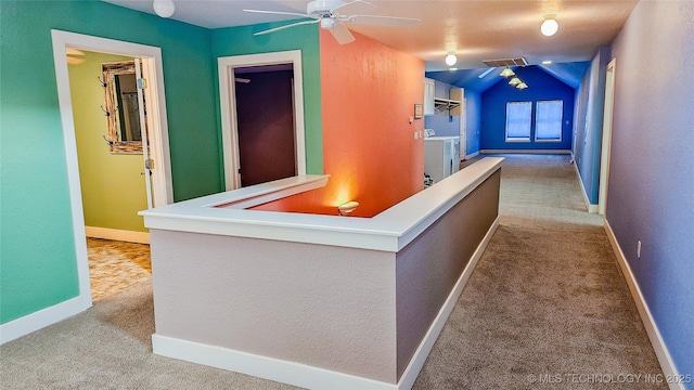 hallway featuring vaulted ceiling, separate washer and dryer, and light colored carpet