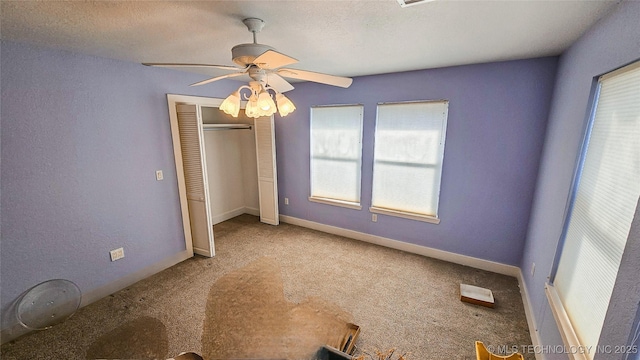 unfurnished bedroom with ceiling fan, carpet floors, a closet, and a textured ceiling