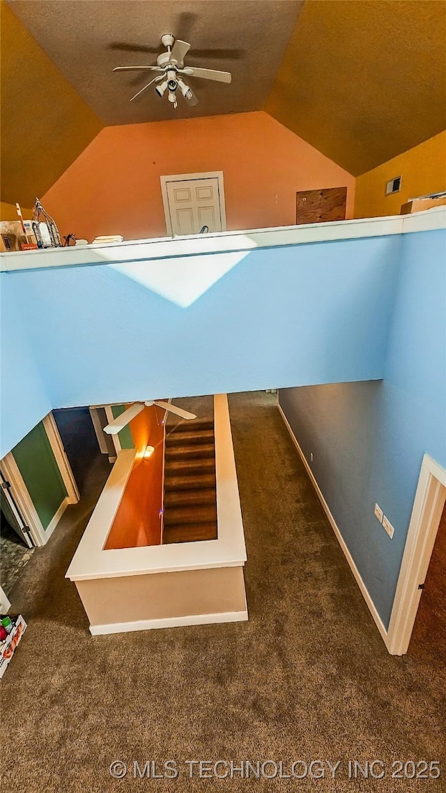 stairs featuring lofted ceiling, ceiling fan, and carpet flooring