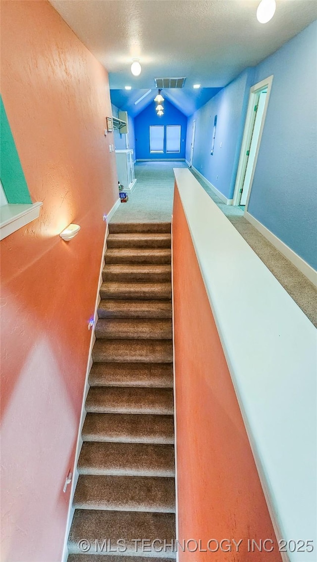 stairs with vaulted ceiling, carpet flooring, and a textured ceiling