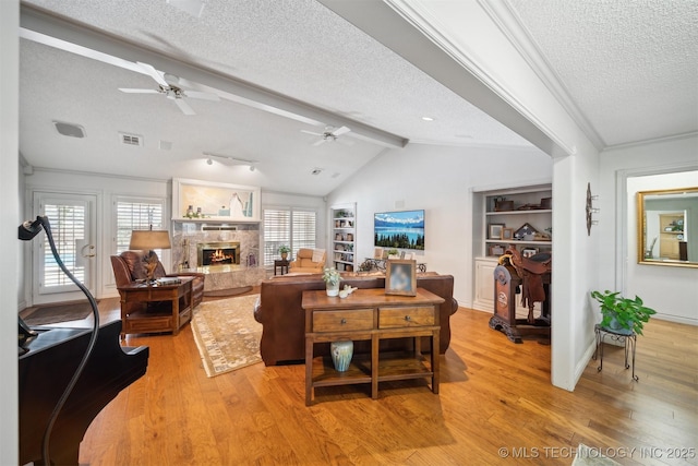 living room with lofted ceiling with beams, a premium fireplace, light hardwood / wood-style floors, and a textured ceiling