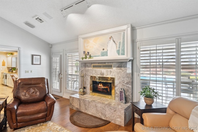 living room featuring vaulted ceiling, a fireplace, hardwood / wood-style flooring, track lighting, and a textured ceiling