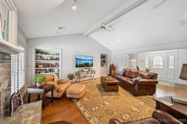 living room with lofted ceiling with beams, wood-type flooring, a healthy amount of sunlight, and a textured ceiling