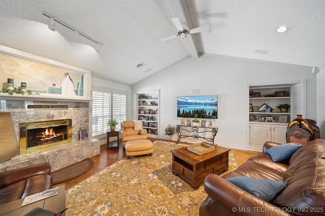 living room featuring a high end fireplace, lofted ceiling with beams, a textured ceiling, and light hardwood / wood-style flooring