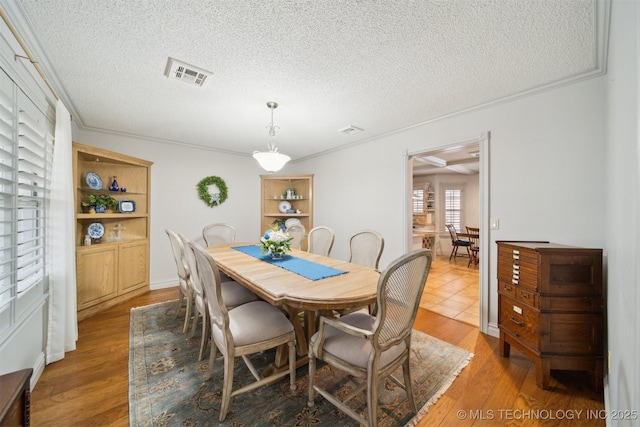 dining room with hardwood / wood-style flooring, crown molding, and a textured ceiling