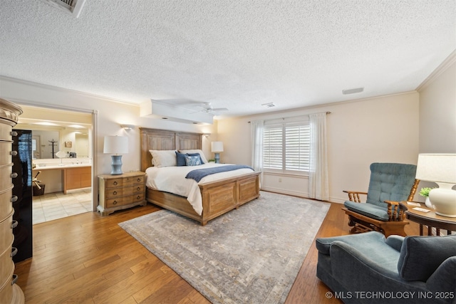 bedroom with sink, ensuite bathroom, ornamental molding, a textured ceiling, and light wood-type flooring