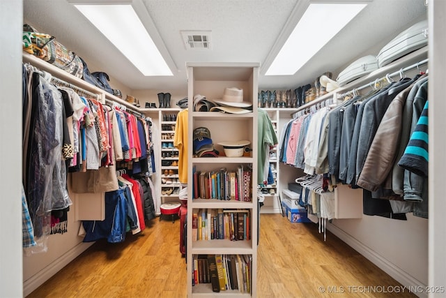 spacious closet with wood-type flooring and a skylight