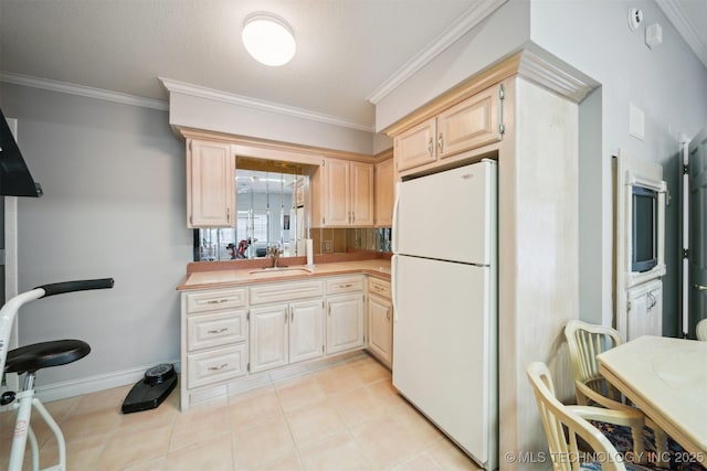 kitchen with sink, crown molding, light tile patterned flooring, and white refrigerator