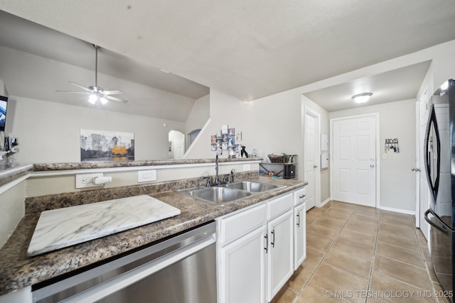 kitchen with sink, black fridge, light tile patterned floors, stainless steel dishwasher, and white cabinets