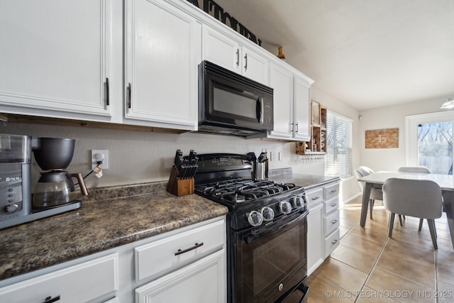 kitchen featuring white cabinetry, dark stone countertops, light tile patterned floors, and black appliances