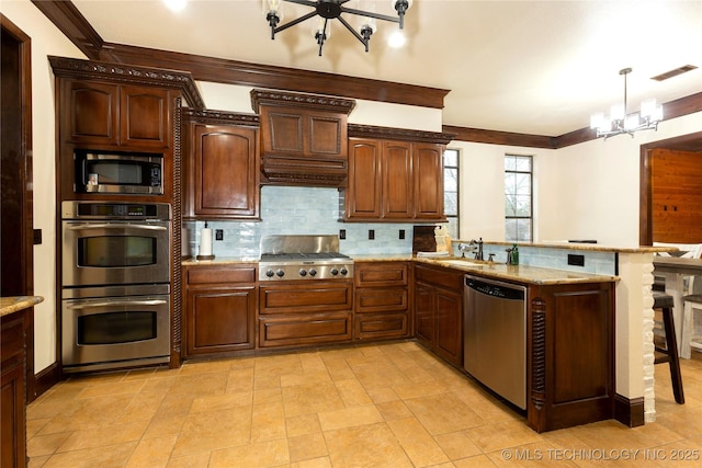 kitchen with sink, a chandelier, appliances with stainless steel finishes, kitchen peninsula, and pendant lighting