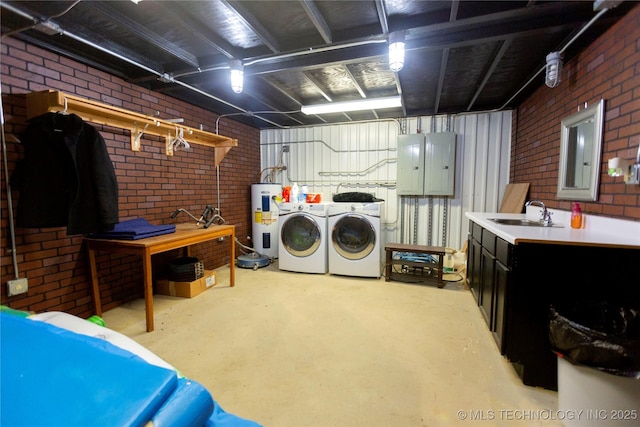 laundry area with sink, electric panel, electric water heater, washer and dryer, and brick wall