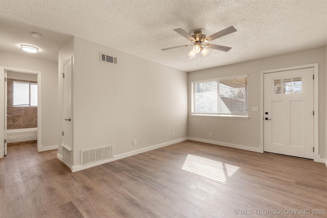 entrance foyer with a textured ceiling, ceiling fan, and light hardwood / wood-style flooring