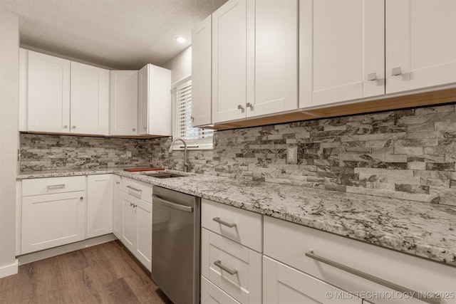 kitchen featuring dark hardwood / wood-style floors, white cabinetry, sink, backsplash, and stainless steel dishwasher