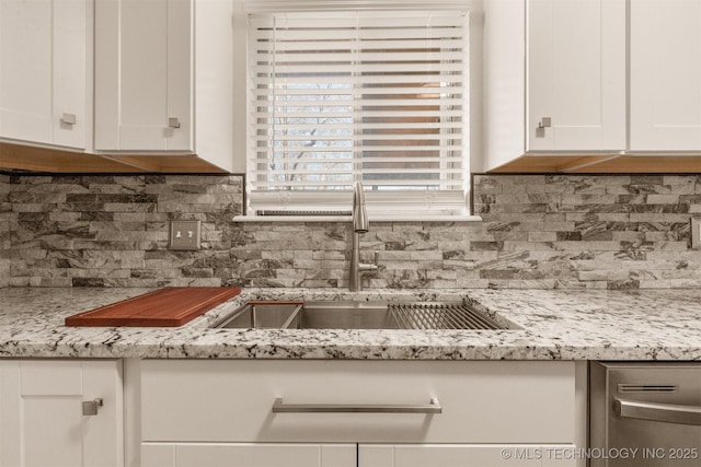 kitchen featuring sink, white cabinets, light stone counters, and decorative backsplash