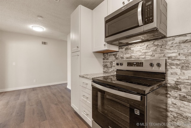 kitchen featuring appliances with stainless steel finishes, tasteful backsplash, a textured ceiling, white cabinets, and dark hardwood / wood-style flooring