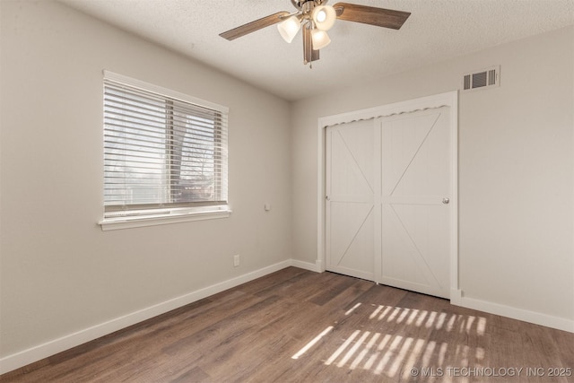 unfurnished bedroom featuring ceiling fan, dark hardwood / wood-style flooring, and a textured ceiling