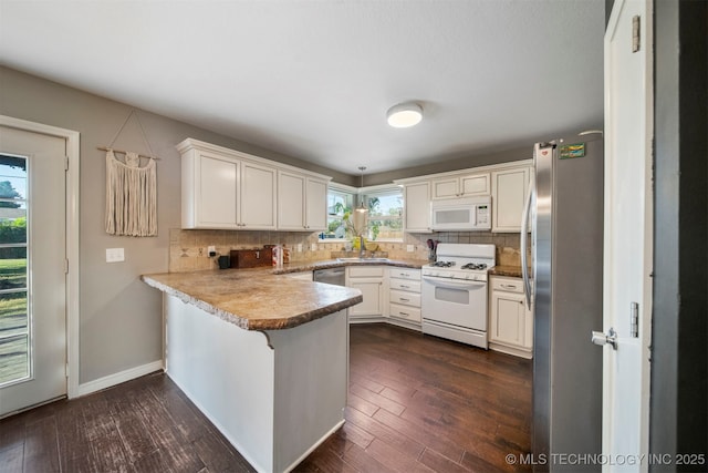 kitchen featuring white cabinetry, dark hardwood / wood-style floors, kitchen peninsula, stainless steel appliances, and backsplash