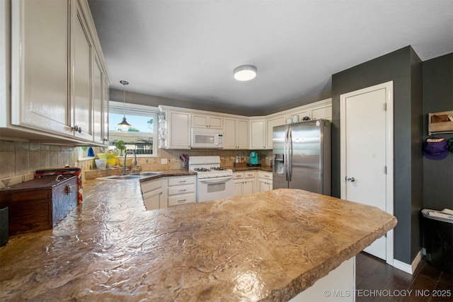 kitchen featuring sink, white appliances, hanging light fixtures, and kitchen peninsula