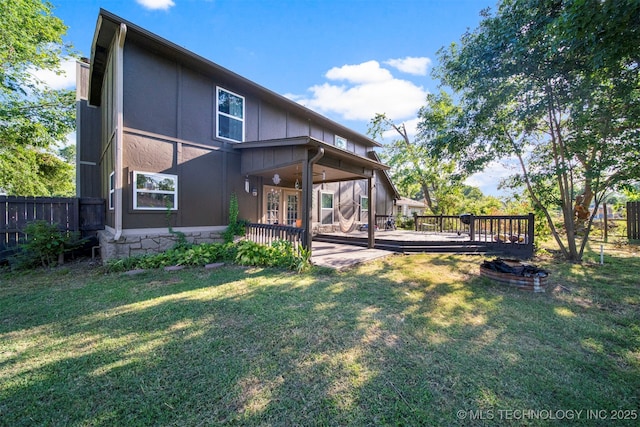 rear view of house with a wooden deck, ceiling fan, and a lawn