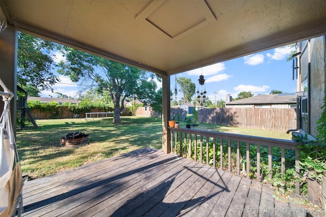 wooden terrace with a trampoline and a yard