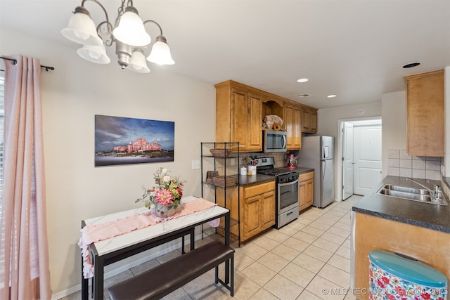 kitchen featuring appliances with stainless steel finishes, hanging light fixtures, light tile patterned flooring, decorative backsplash, and a chandelier