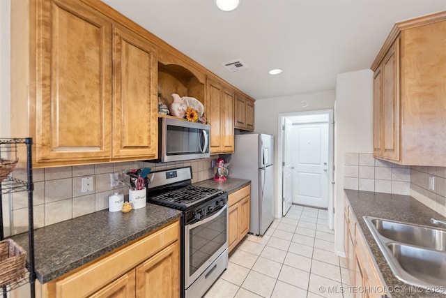 kitchen with stainless steel appliances, tasteful backsplash, sink, and light tile patterned floors