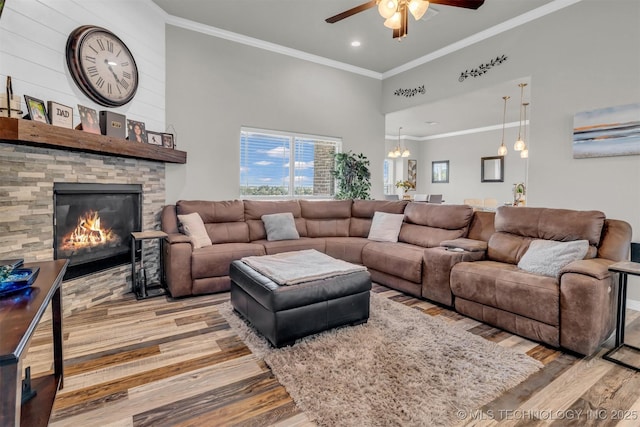 living room featuring a stone fireplace, ornamental molding, a high ceiling, and light wood-type flooring