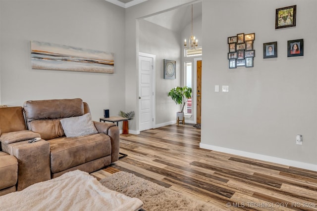 living room featuring an inviting chandelier, wood-type flooring, and a high ceiling