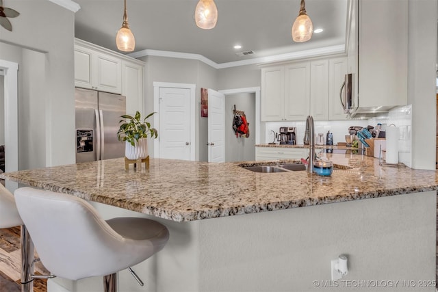 kitchen with white cabinetry, light stone counters, appliances with stainless steel finishes, kitchen peninsula, and pendant lighting