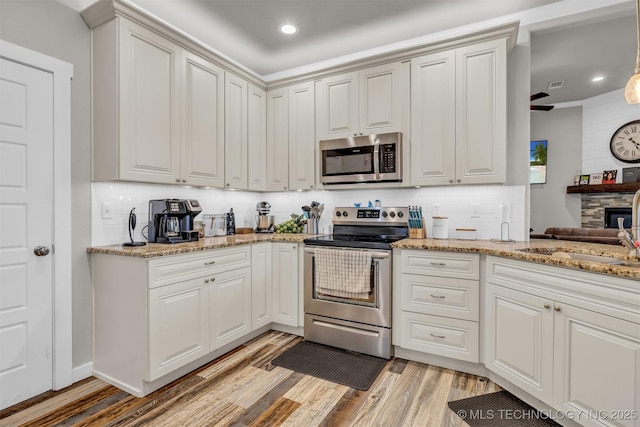 kitchen with stainless steel appliances, white cabinetry, sink, and light wood-type flooring