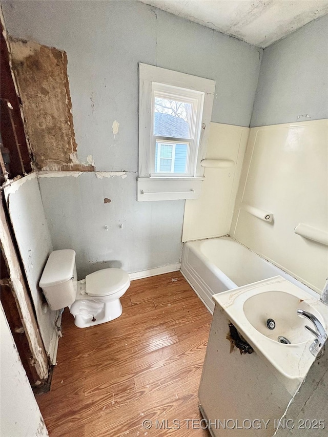 bathroom featuring hardwood / wood-style flooring, toilet, a bathing tub, and sink